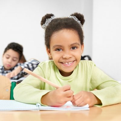 Schoolgirl smiling, posing in classroom at primary school